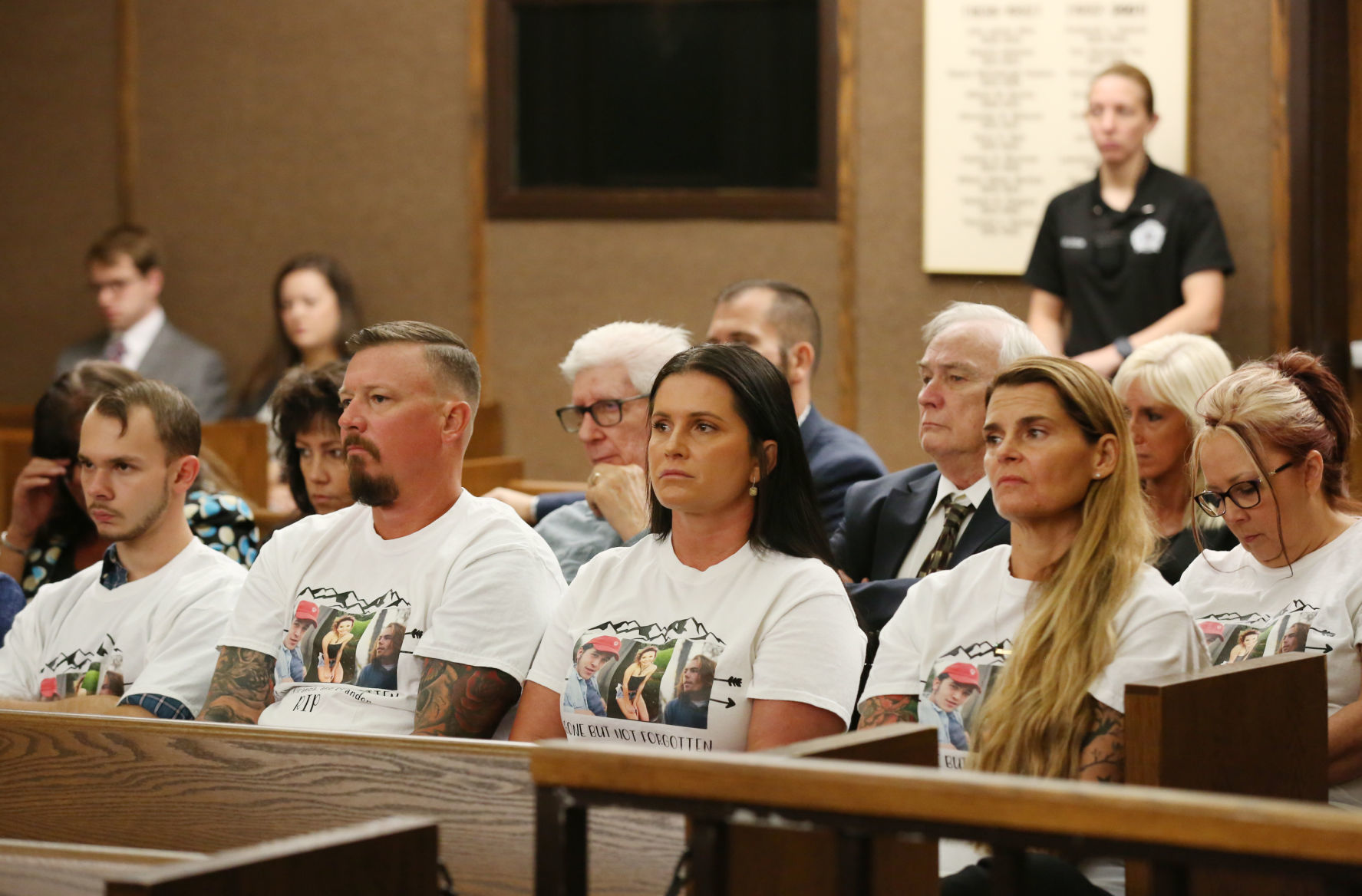People in the gallery wear shirts commemorating the victims
